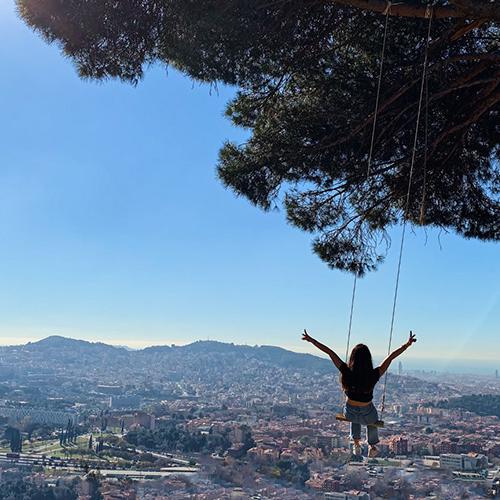 woman on a tree swing overlooking a city